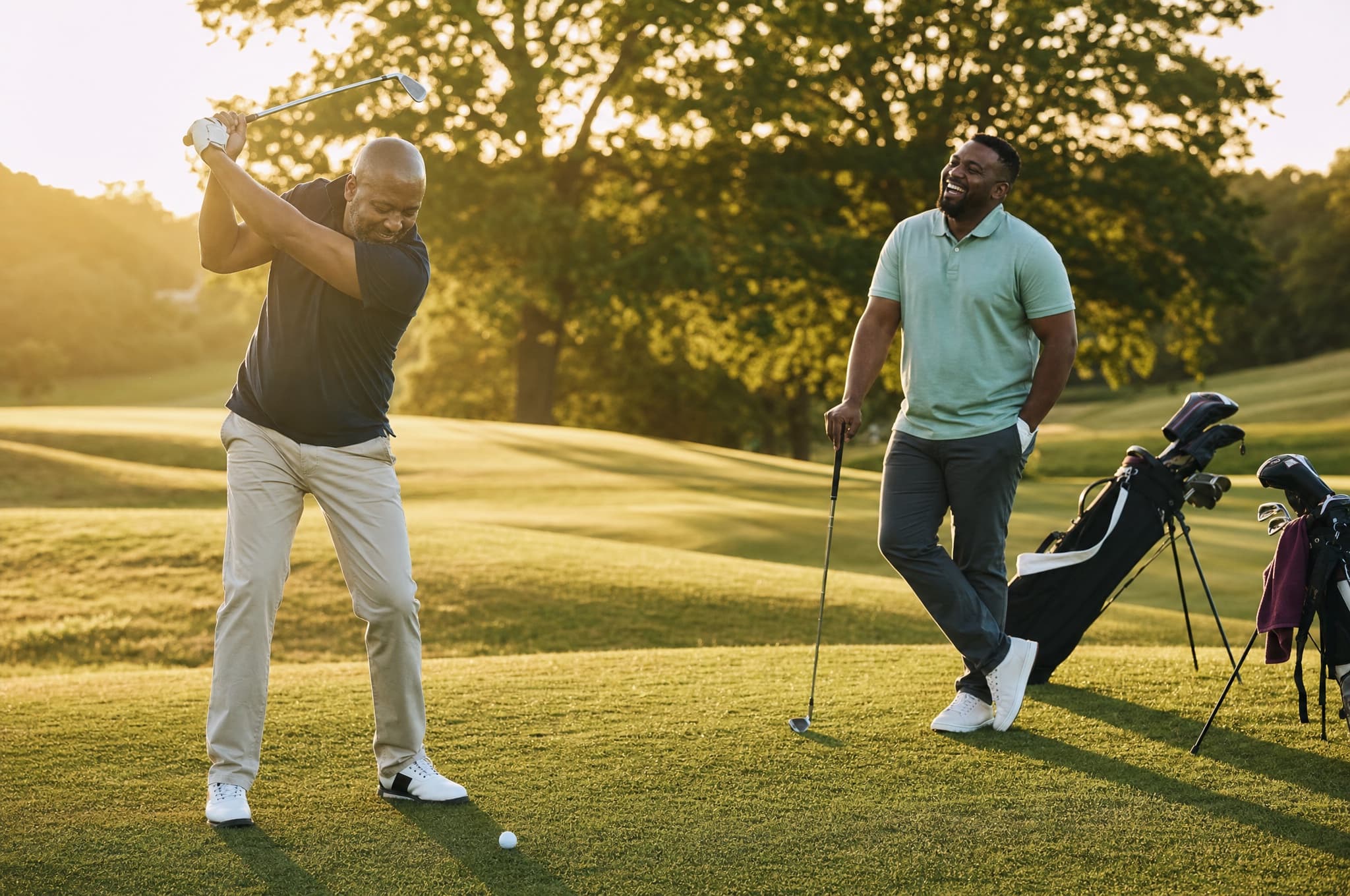 Two fathers golfing together on a green fairway at golden hour